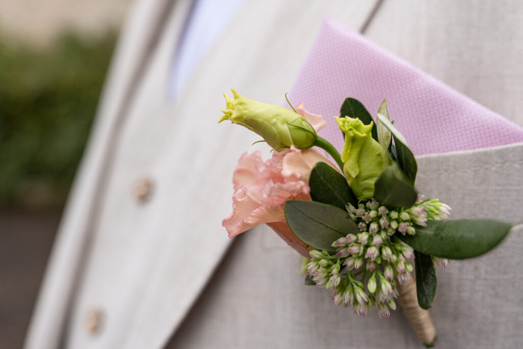 Gros plan sur la poche du marié portant une fleur pendant la séance couple