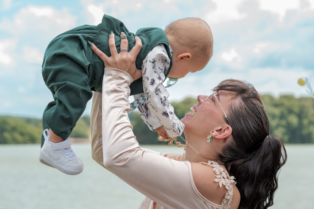 Soeur du marié tenant son neveu de 1 an dans à bout de bras et riant aux éclats