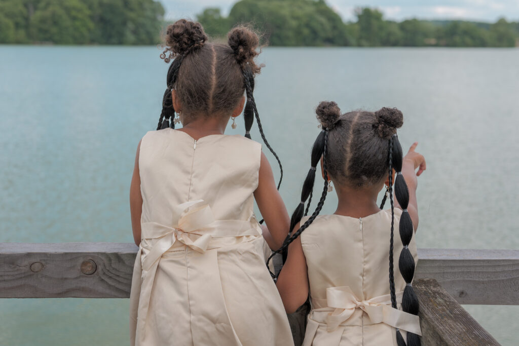 Deux petites filles de dos observant l'étang, l'une pointant quelque chose du doigt