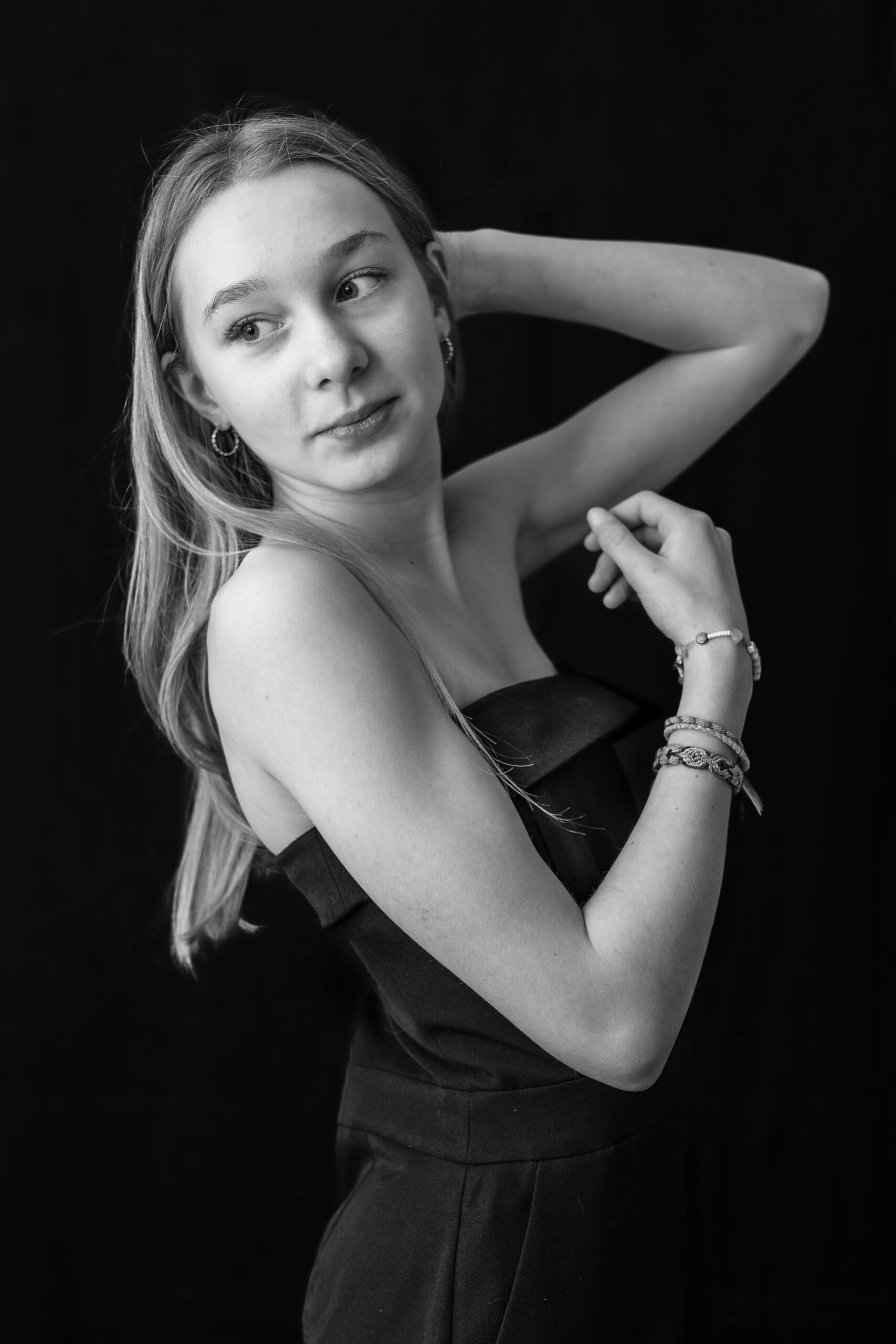 Portrait artistique en noir et blanc sur fond noir d'une jeune fille posant de manière à former des formes géométriques