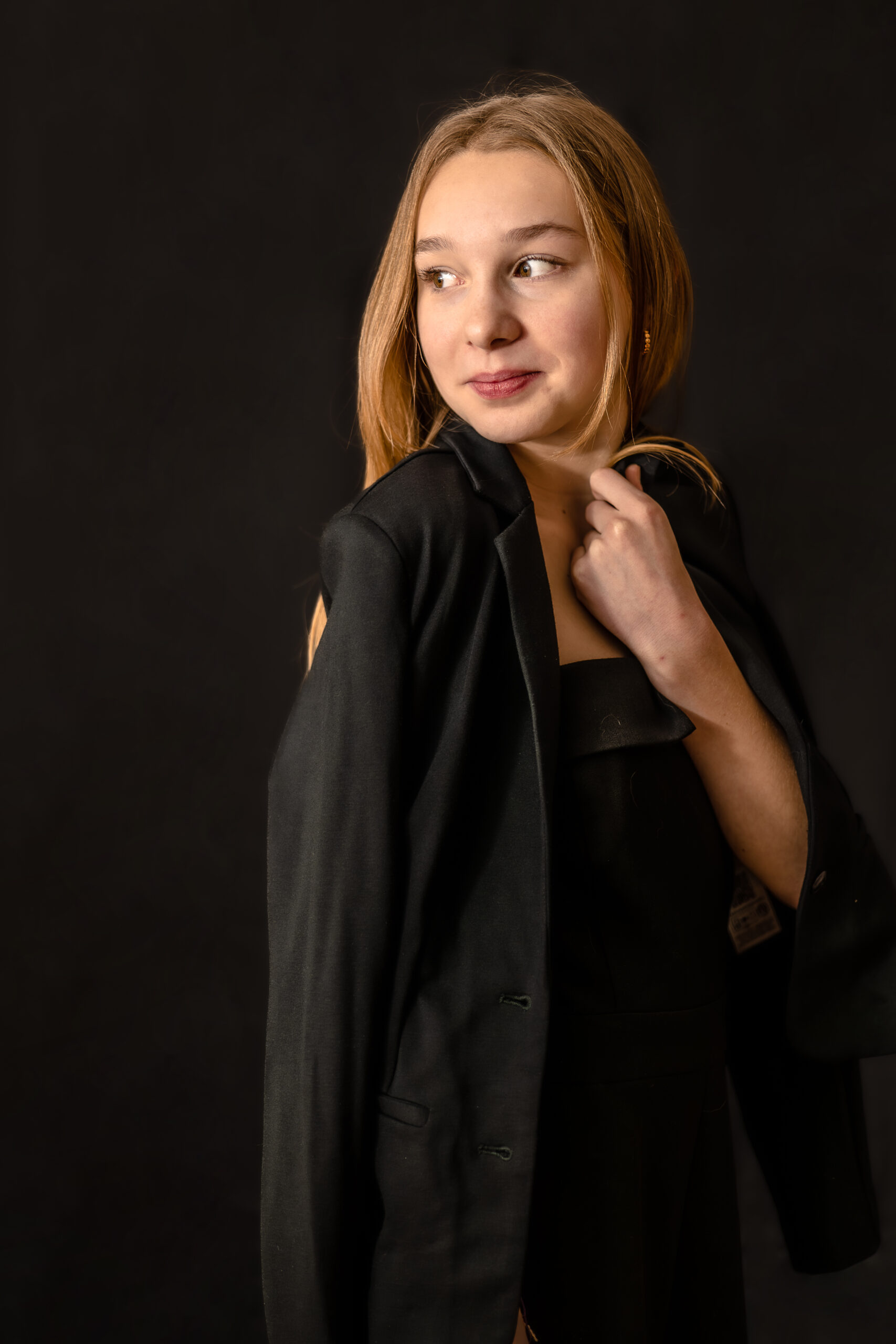 Portrait d'une jeune fille de 3/4, le visage et le regard tourné vers la gauche avec une veste simplement déposée sur ses épaules