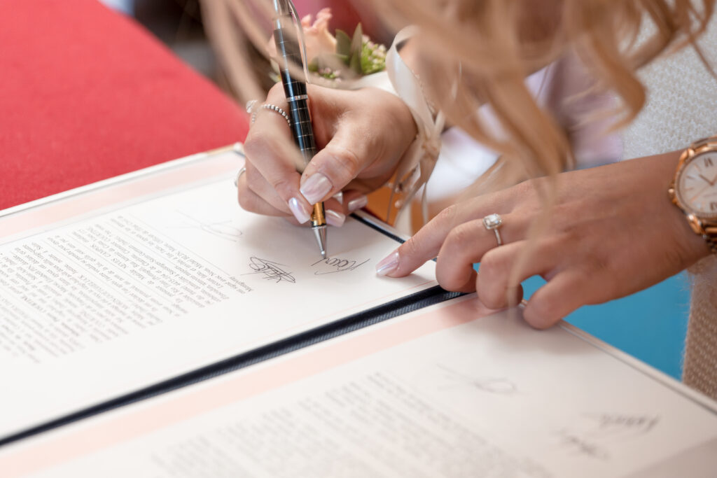Gros plan sur les mains de la témoins de mariage et aussi fille du marié montrant sa signature lors de la cérémonie à la Mairie