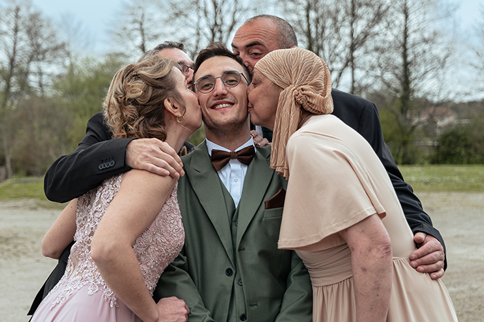 Le marié reçoit lors d'une photo de groupe les baisers de sa famille sur chaque joue