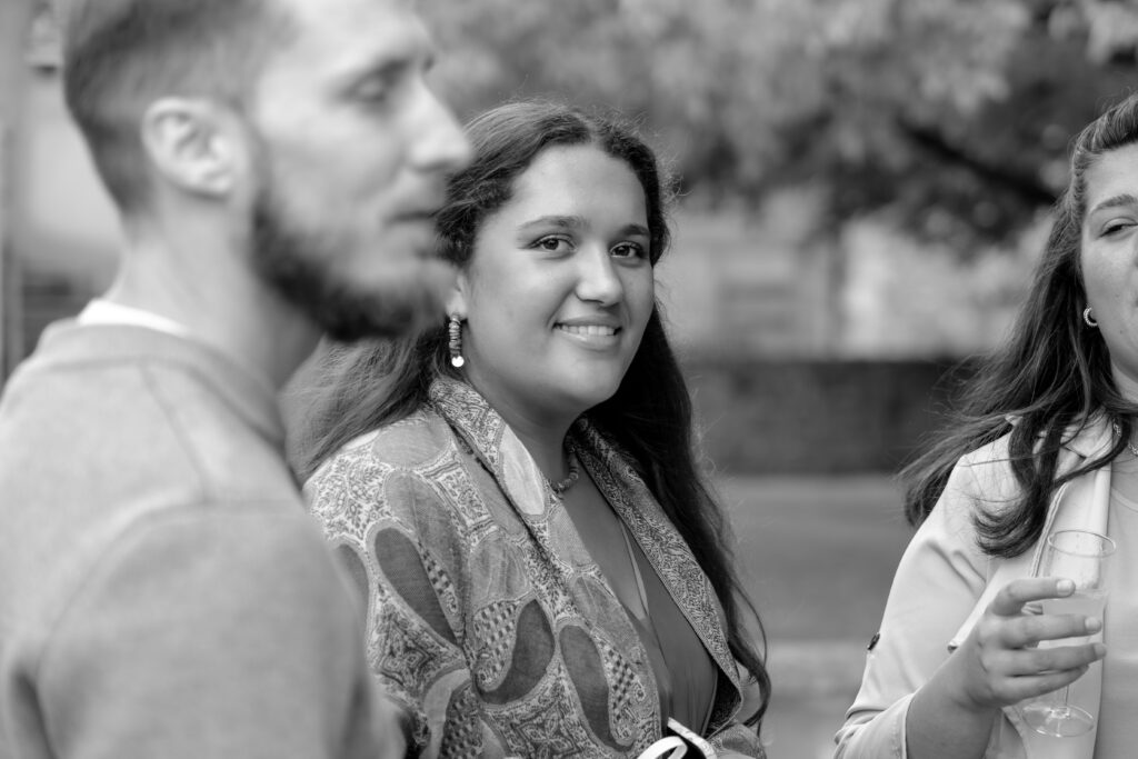 Portrait en noir et blanc de la fille de la mariée avec un premier plan flou sur un invité mettant en avant le sujet principal de la photo