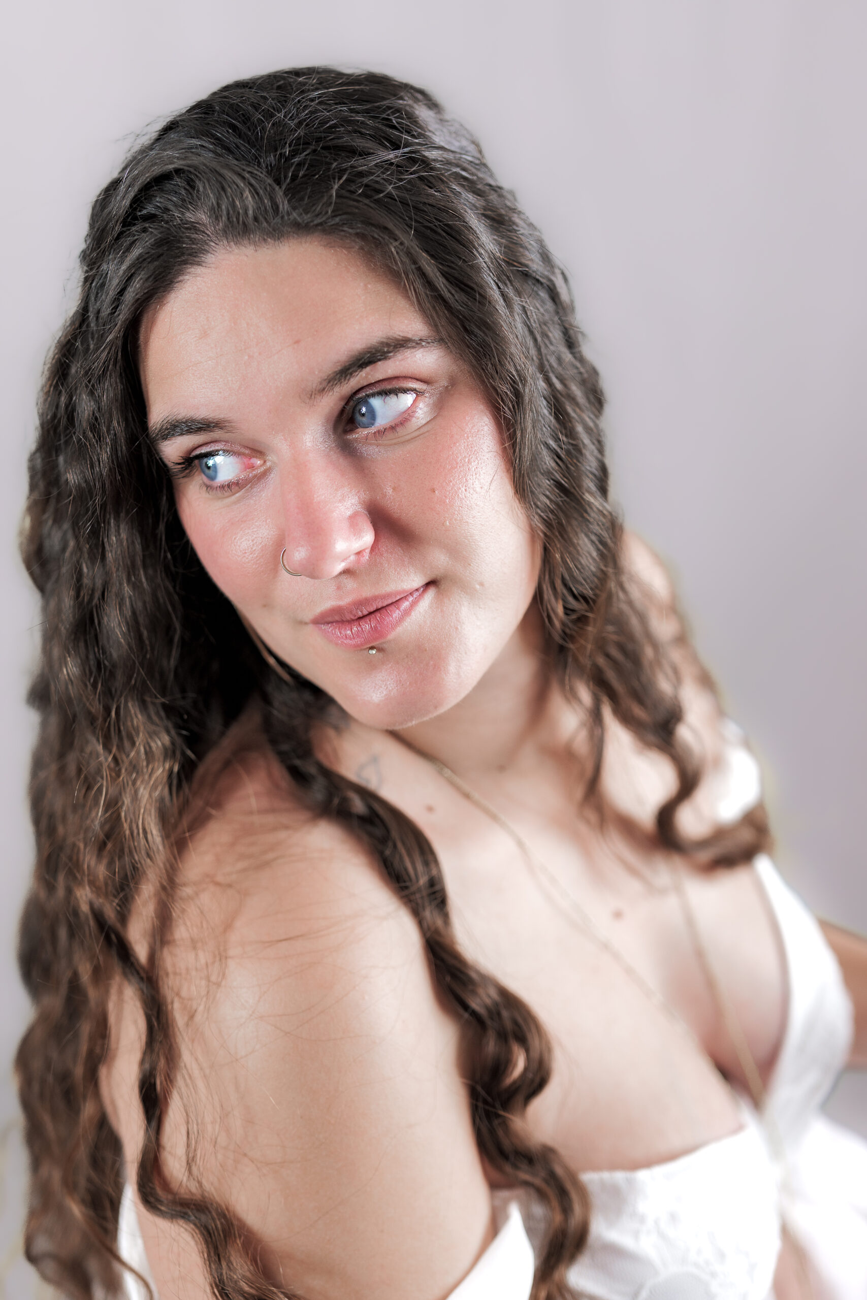 Portrait d'une femme enceinte vue plongeante tournant la tête et regardant vers la gauche avec un éclairage doux et un fond rosé