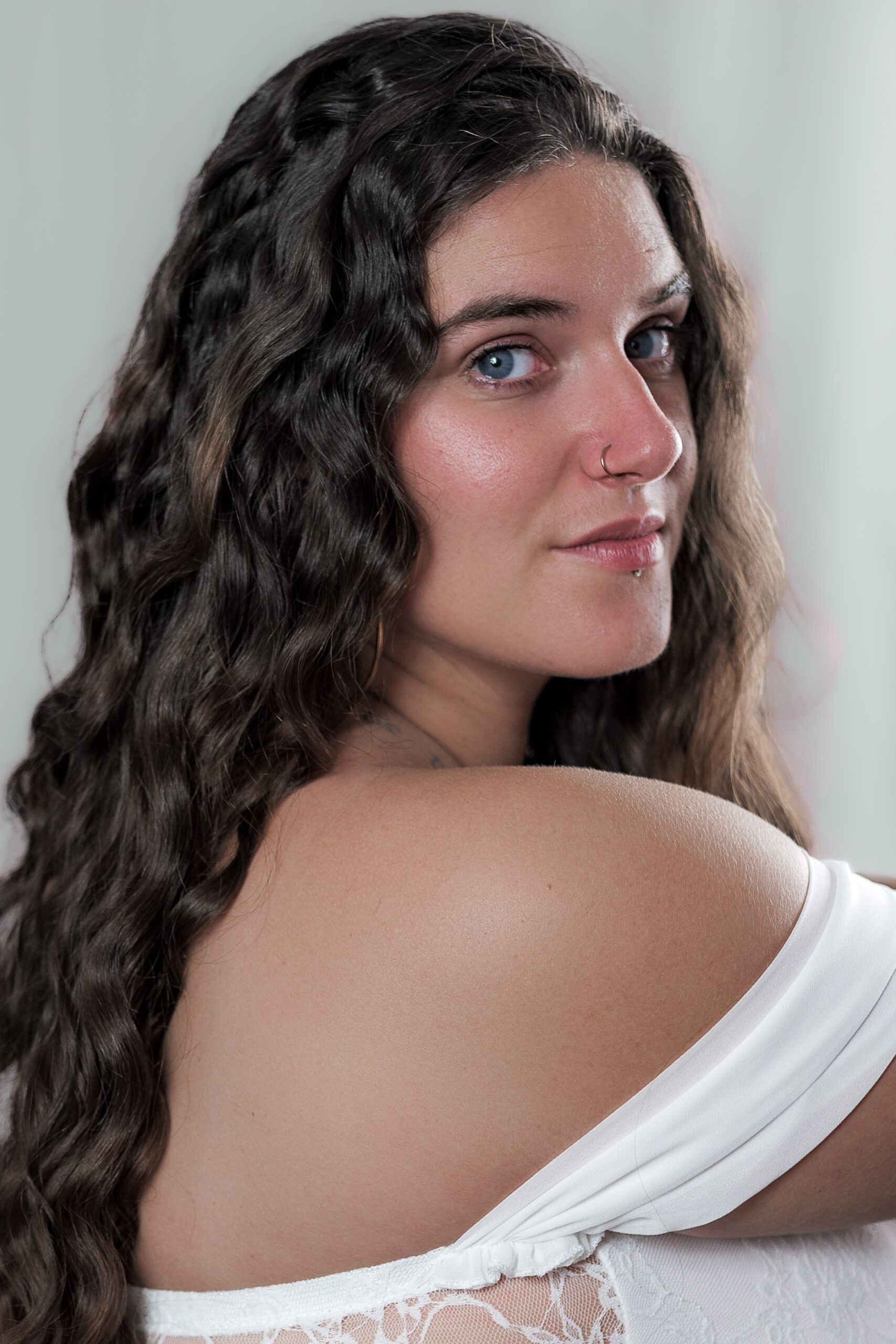 Portrait d'une femme 3/4 de dos regardant l'objectif avec un éclairage doux et un fond bleuté