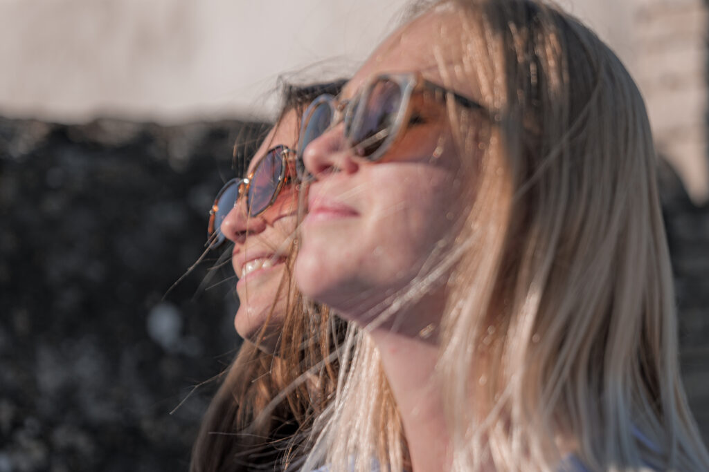 Photographie des visages de deux femmes portant des lunettes de soleil et prenant un bain de soleil 
