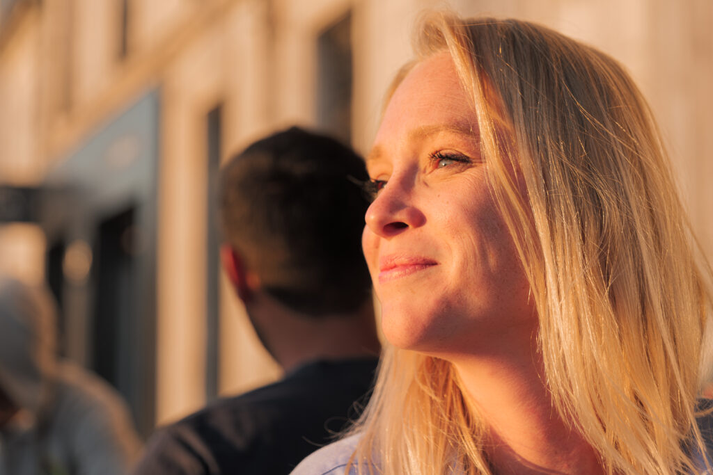 Femme blonde souriant et regardant vers le couché du soleil