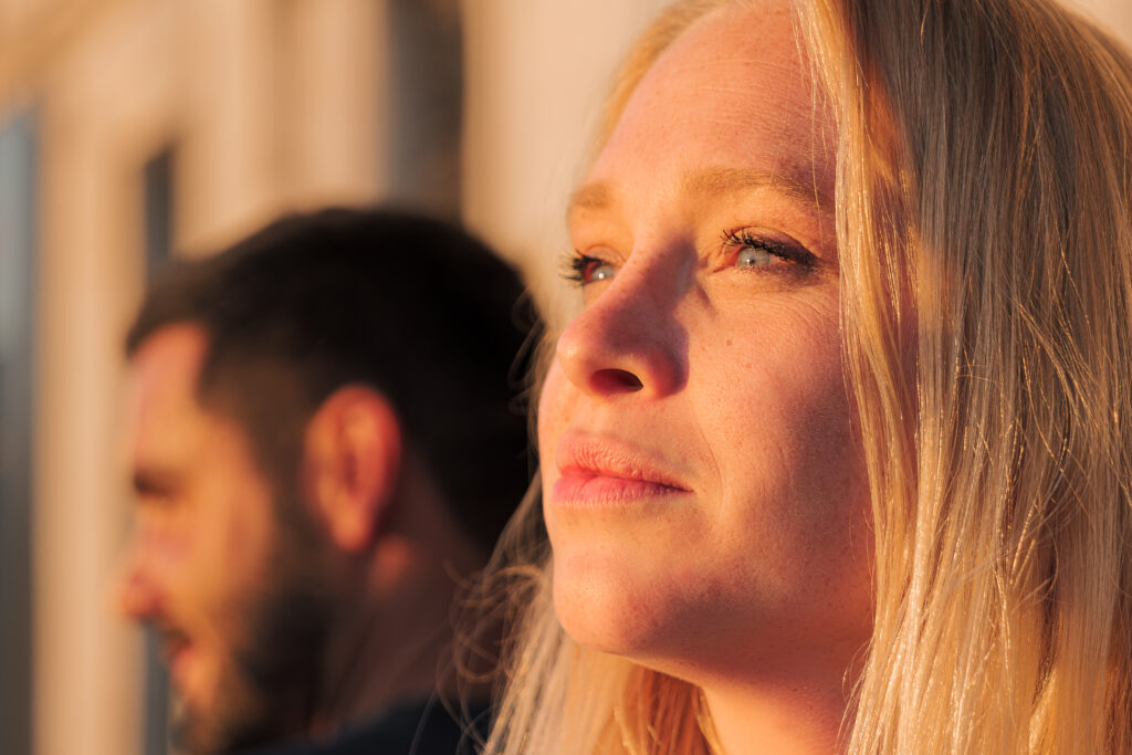Femme blonde aux yeux bleu en plan rapproché regardant vers le couché du soleil sur le port avec un flou d'arrière plan