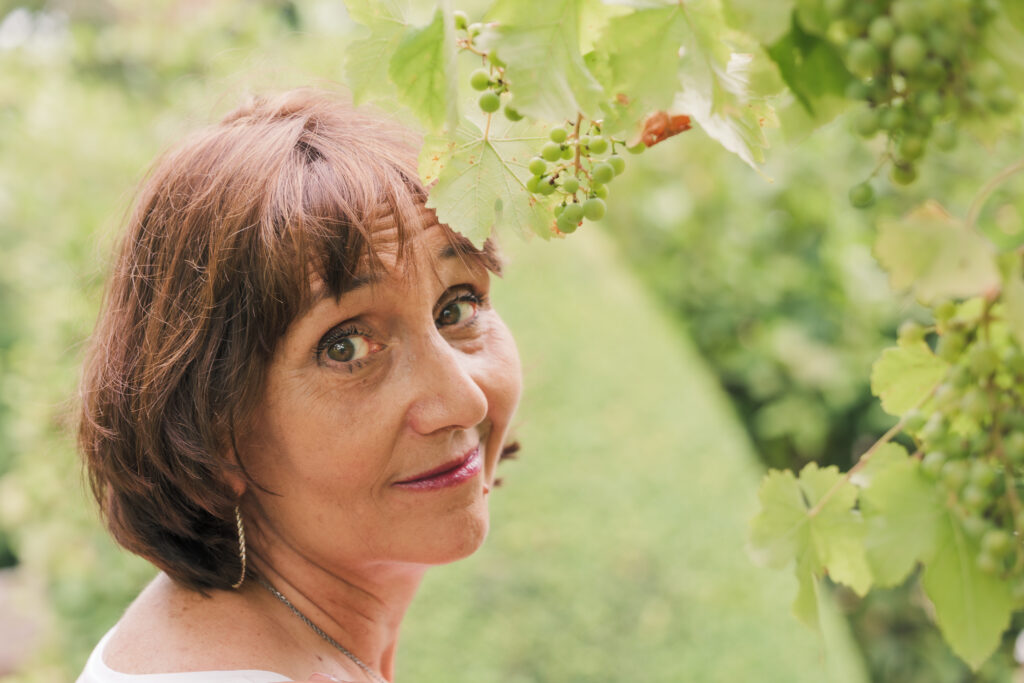 Portrait d'une femme d'âge moyen brune aux yeux noisettes, photographiée en Creuse avec un arrière plan flou de verdure
