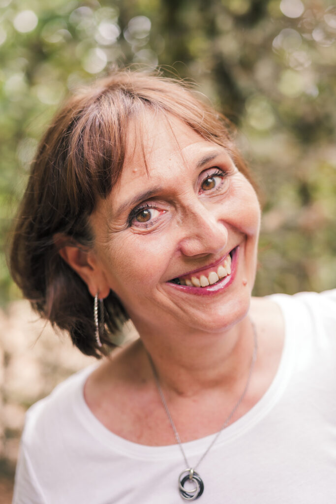 Portrait d'une femme d'âge moyen brune aux yeux noisettes, photographiée en Creuse avec un arrière plan flou de verdure