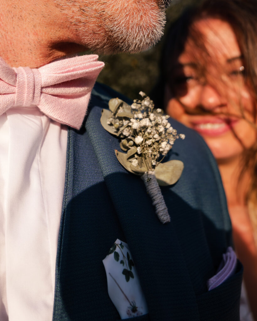 Plan rapproché sur les détails du costume du marié, portant à la poche un mini bouquet de fleur séchées