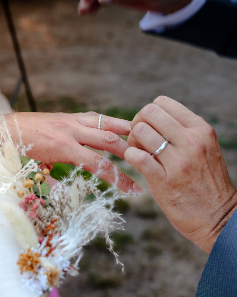 Plan rapproché des mains des mariés s'échangeant les alliances après la cérémonie laïque