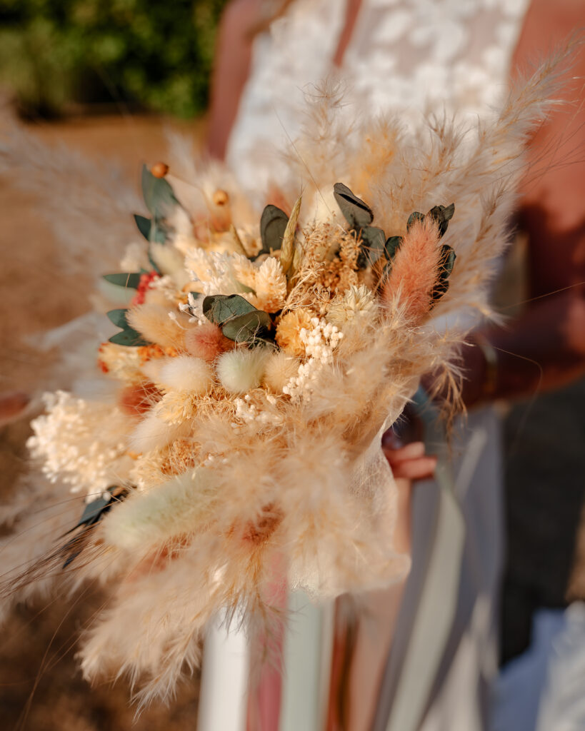 Plan rapproché sur le bouquet des fleurs séchées de la mariée dans des tons beiges pastels et orangés