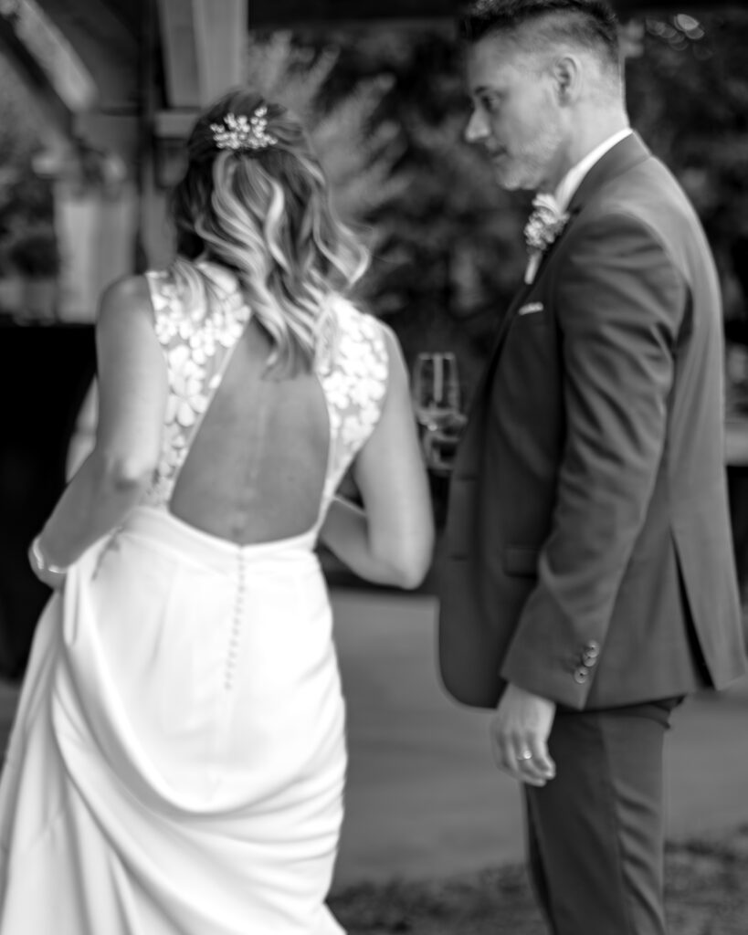 Portrait de dos de la mariée et du profil du marié échangeant quelques mots pendant le vin d'honneur