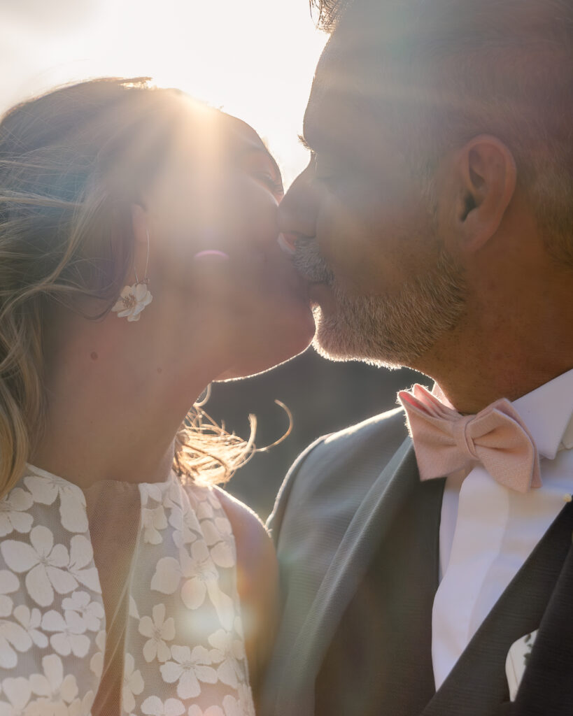Portrait en contre-jour d'un couple de jeune mariés s'embrassant au coucher du soleil.